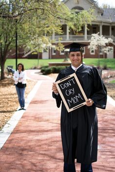 a man in cap and gown holding a sign that says don't cry mom