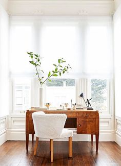 a white chair sitting in front of a desk with a potted plant on it