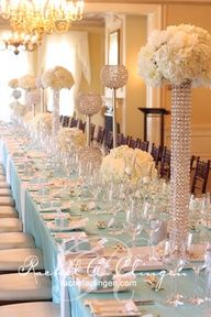 a long table is set with white flowers and crystal vases