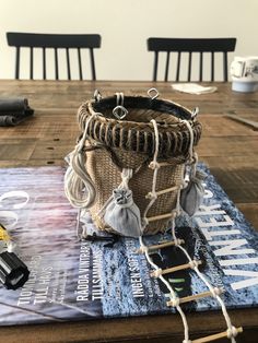 a wooden table topped with a basket on top of a book next to a pair of scissors