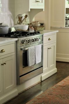 a stove top oven sitting inside of a kitchen next to white cabinets and counter tops