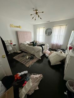 a room with two beds and clothes on the floor