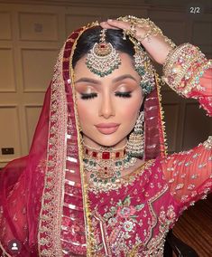 a woman in a red and gold bridal outfit with her hands on her head