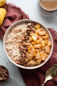 a bowl filled with oatmeal and nuts next to two cups of coffee