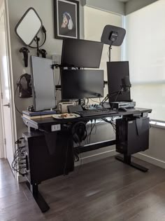 a computer desk with multiple monitors and keyboards on it, in front of a window