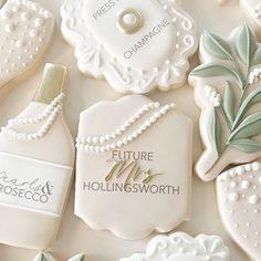 decorated cookies with white frosting and green leaves are arranged in the shape of women's perfume bottles