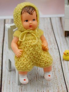 a small doll sitting on top of a white chair next to a rubber duck toy