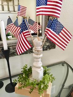 an american flag centerpiece is displayed on a glass table with candles and greenery