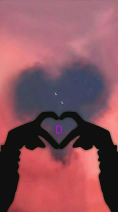 two hands making a heart shape with the letter d in front of a pink sky