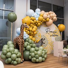 a giraffe and zebra are on display in front of balloons at a children's birthday party