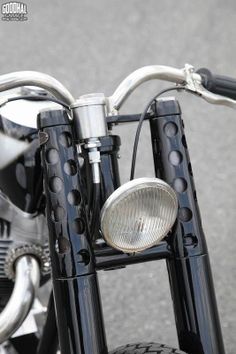 the front end of a black motorcycle with a light on it's handlebars