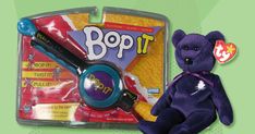 a purple teddy bear with a magnifying glass in it's mouth next to a toy