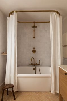 a white bath tub sitting next to a wooden stool