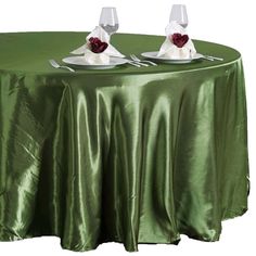 two wine glasses sitting on top of a table covered in a green cloth with white napkins