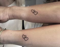 two women with matching tattoos on their arms, both have hearts drawn on the arm