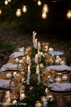 an outdoor dinner table set with candles and plates