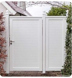 an open white gate in front of a house