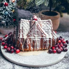 a cake with icing and cranberries on a plate next to a christmas tree