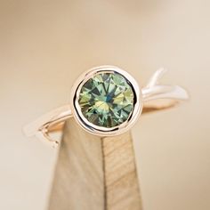 a close up view of a ring with a green diamond in it's center