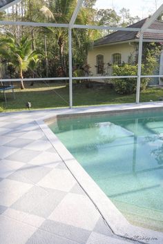 an empty swimming pool in the middle of a backyard with a tiled floor and glass walls