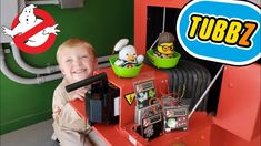 a young boy sitting on top of a red table next to a pile of toys