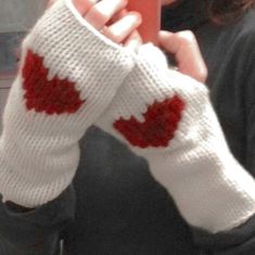 the woman is holding her cell phone and wearing knitted gloves with maple leaves on them