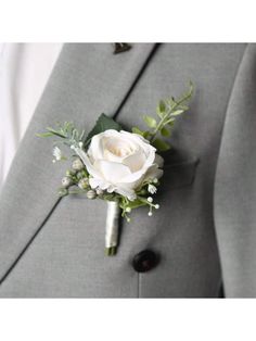 a boutonniere with a white rose and greenery on the lapel