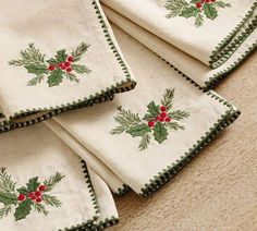 napkins with holly and red berries on them are sitting on the floor next to each other