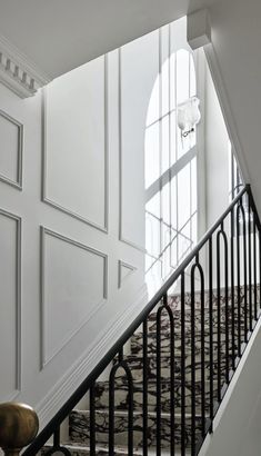 a staircase with white walls and black iron railings