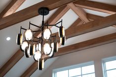 a chandelier hanging from the ceiling in a room with wooden beams and windows