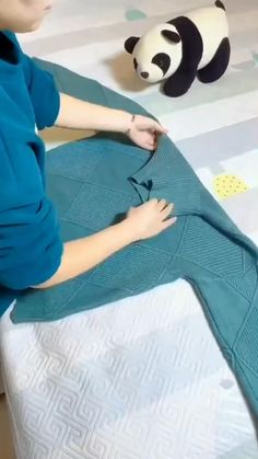 a young boy is making a knitted mermaid tail for his stuffed animal panda bear