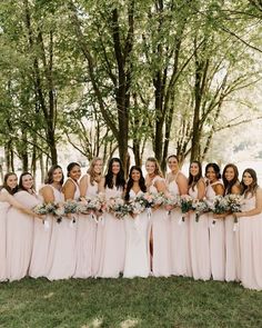 a group of women standing next to each other in front of trees with flowers on them