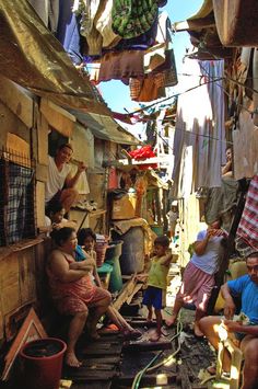 a group of people hanging out in an alleyway with clothes drying on the line