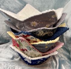 a stack of cloth covered bowls sitting on top of a blue sheet filled with fabric