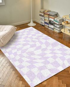 a white and purple rug sitting on top of a wooden floor next to a lamp