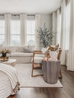 a living room filled with white furniture and windows covered in shades of grays, whites and neutrals