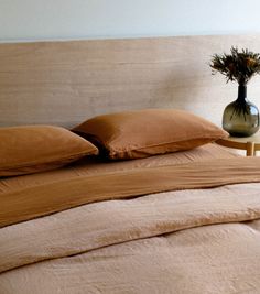 a bed topped with two pillows and a vase filled with flowers