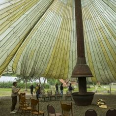 people are standing under an umbrella with chairs around it