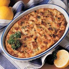 a casserole dish with meat and vegetables in it on a table next to lemons