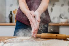 a person is kneading dough on top of a wooden table in the kitchen