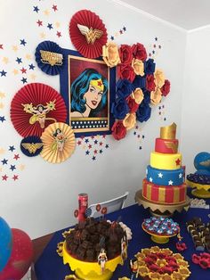 a table topped with cakes and desserts next to a wall decorated with paper fans