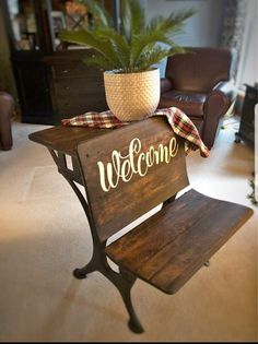 a wooden welcome sign sitting on top of a table next to a potted plant