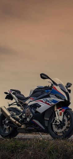 two motorcycles parked next to each other on the side of a road in front of a cloudy sky