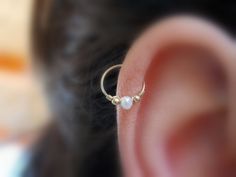 a close up of a person's ear with a single pearl bead on it