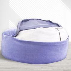 a purple bean bag sitting on top of a wooden floor next to a white wall