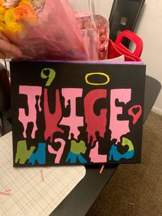 a sign that says fudge and has been decorated with pink, blue, yellow and green paint