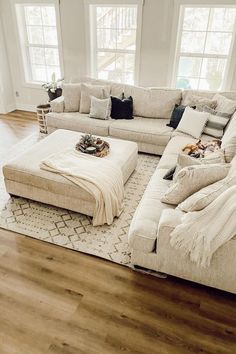 a large sectional couch sitting on top of a wooden floor in front of two windows