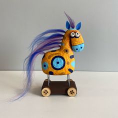 a wooden toy horse with blue hair on it's head