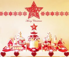 a table topped with lots of cakes and cupcakes next to a christmas tree