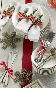 the table is set for christmas dinner with red and white napkins, silverware